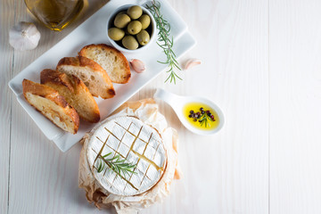 Baked camembert cheese. Fresh Brie cheese and a slice on a wooden board with nuts, honey, rosemary,...