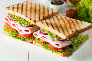 Close-up photo of a club sandwich. Sandwich with meat, prosciutto, salami, salad, vegetables,...