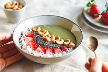 Green smoothie bowl with coconut cream, banana, strawberry, cashew and chia seeds. Healthy vegan eating.