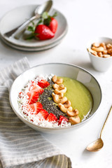 Green smoothie bowl with coconut cream, banana, strawberry, cashew and chia seeds. Healthy vegan eating.