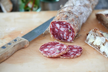 Salami with butter bread to eat on a wooden board with knife