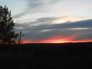 Red sunset in the field with heavy clouds.