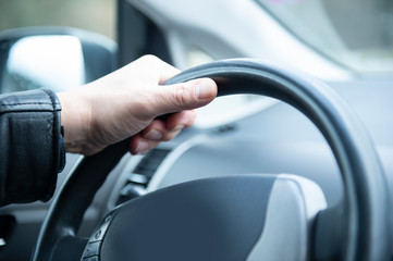 Mann hält entspannt das Lenkrad seines Autos