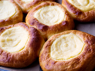 Open buns with cottage cheese (vatrushka) lying on a tray after baking. Сlose up.