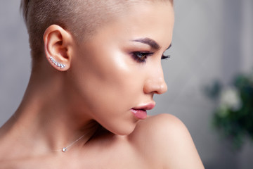 Closeup sexy blonde model with bright make-up, bare shoulders and short hair with shaved temples in...