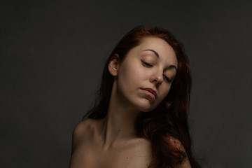 Fototapeta premium Sexy tan woman closed her eyes and posing on a camera. Black background