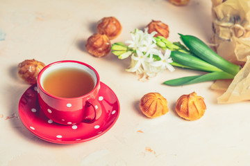 Red in white dotted cup of tea, profiteroles and hyacinths