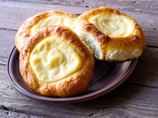 Open buns with cottage cheese (vatrushka)lying in a clay plate on a wooden table.  Rustic Photography. Сlose up.
