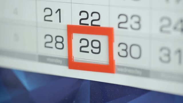 Woman's hand in office changes date at wall calendar. Changes 28 to 29