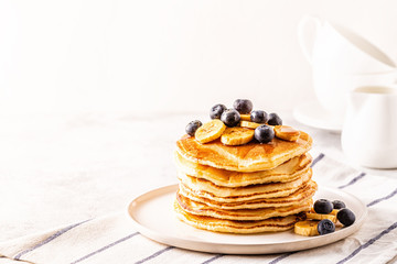 Pancakes with banana,  blueberries on white plate.