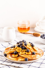 Obraz na płótnie Canvas Pancakes with banana, blueberries on white plate.
