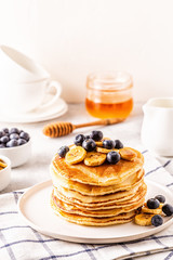 Pancakes with banana,  blueberries on white plate.