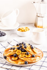 Pancakes with banana,  blueberries on white plate.