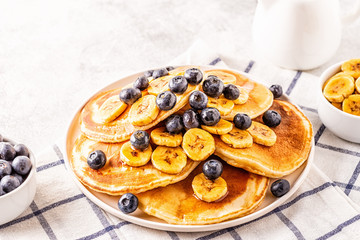 Pancakes with banana,  blueberries on white plate.