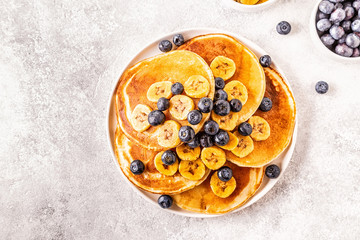 Pancakes with banana,  blueberries on white plate.