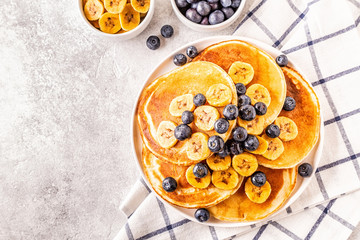 Pancakes with banana,  blueberries on white plate.