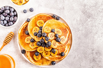 Pancakes with banana,  blueberries on white plate.
