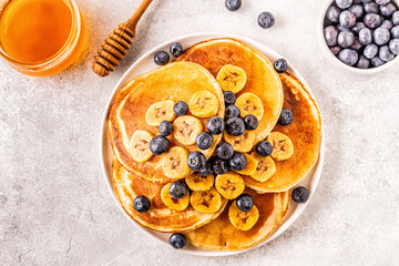 Pancakes with banana,  blueberries on white plate.