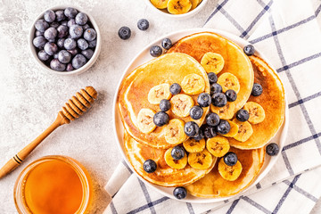 Pancakes with banana,  blueberries on white plate.