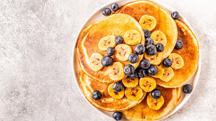 Pancakes with banana,  blueberries on white plate.