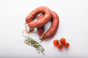Food, meat and delicious concept - sausages made with horse meat with tomatoes on table