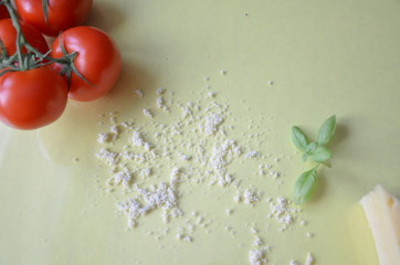 Italian food background with tomatoes, basil, parmesan. Ingredients onellow table Copy space Top view