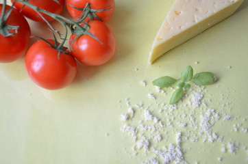 Italian food background with tomatoes, basil, parmesan. Ingredients onellow table Copy space Top view