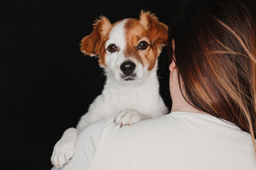 young woman and her cute dog. black background. studio shot. love for animals concept