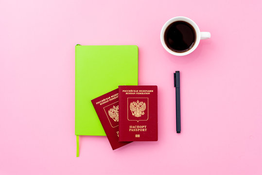 Russian international passports, green notebook and a cup of cofee on pink background. Concept for travel agencies