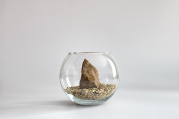 Granite stone on sand in glass aquarium. Minimal concept.