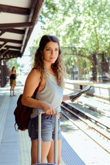 Woman with suitcase waiting the train.