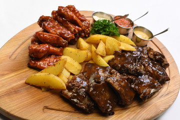 A large meat dish with potatoes. Wooden board on a white background.