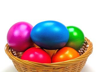 Bunte Ostereier im Korb vor weißem Hintergrund
