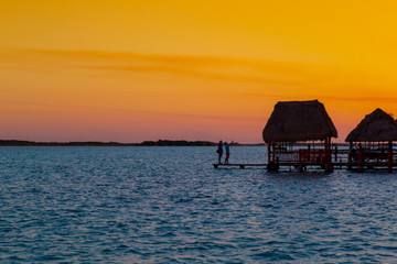 sunset in Lagoon of Seven Colors in Bacalar,couple watching the sun,Quintana Roo, México.