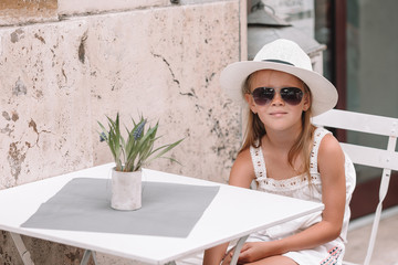 Fototapeta na wymiar Little girl at outdoor cafe on warm summer day