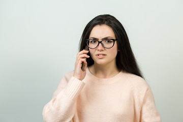 Young beautiful woman using mobile phone studio on white color background. Looking attentively at screen of cellphone, browsing web pages. 