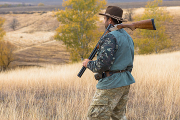 Hunter with a hat and a gun in search of prey in the steppe	