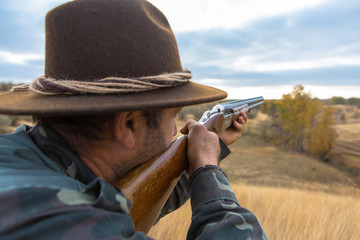 Hunter with a hat and a gun in search of prey in the steppe	