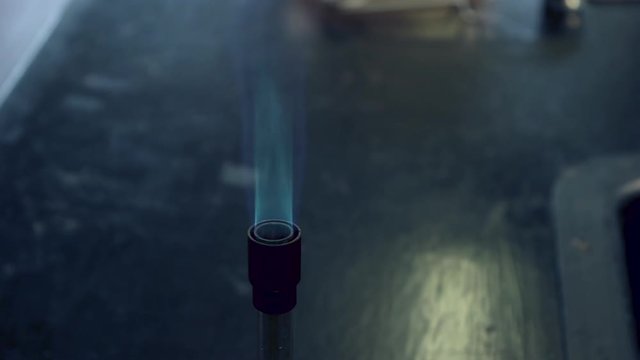 Close up of blue bunsen burner flame followed by strontium flame test burning red
