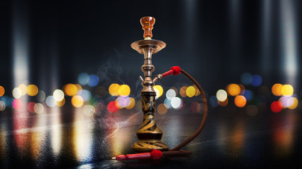 Hookah with smoke on the background of an empty scene, wet asphalt and colored neon light, blurry...