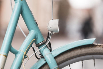 close up front of a turquoise bike with front light, cables, wheel and mudguard isolated
