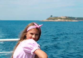 happy little girl sailing in a boat smiling at the sea on summer cruise