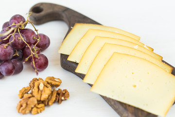 Fresh products. Sliced cheese with grapes and nuts on rustic table.