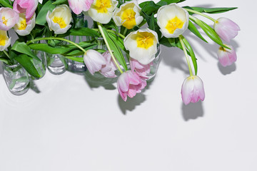 Top view of the bouquets of tulips in glass jars on a white background.