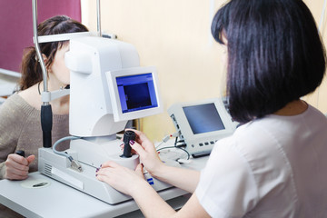 Young beautiful woman doctor checks the vision of a young woman in a modern clinic. Doctor and patient in an ophthalmologic clinic
