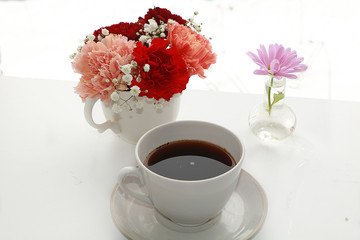 cup of coffee and a bouquet of flowers on a white background, a beautiful morning and the arrival of spring
