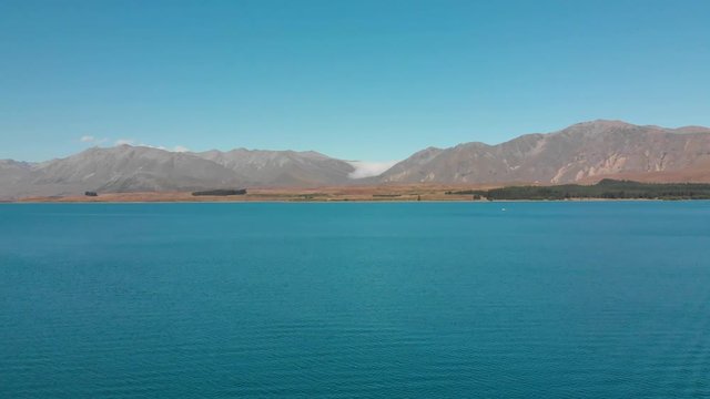 SLOWMO - Aerial shot of Lake Tekapo, New Zealand and its Beautiful Turquoise Blue Water wiht mountains in background