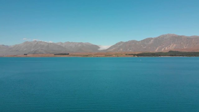 Aerial shot of Lake Tekapo, New Zealand and its Beautiful Turquoise Blue Water wiht mountains in background