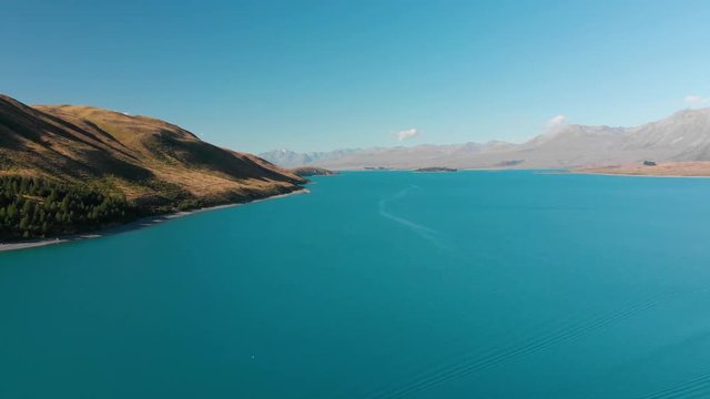 SLOWMO - Aerial shot of Lake Tekapo, New Zealand and its Beautiful Turquoise Blue Water wiht mountains in background