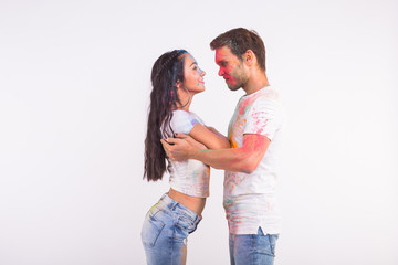 Holiday, social dance, holi and people concept - Happy couple having fun covered in paint and dancing bachata or kizomba on white background